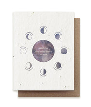 Load image into Gallery viewer, A greeting card made of seed paper shows an illustration of a full moon in purplish-gray, with the phases of the moon illustrated and labeled around it. In the center of the full moon are the words &quot;wishing you many more moons.&quot;
