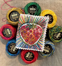 Load image into Gallery viewer, A small needlebook stitched with a strawberry and rainbow design, surrounded by spools of perle cotton thread.
