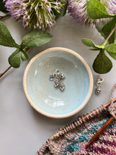 Load image into Gallery viewer, Sky blue ceramic notions bowl holding silver acorn stitch markers.
