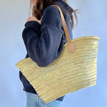 Load image into Gallery viewer, Person holds a French market basket - naturally woven grass with leather handles
