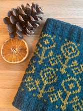 Load image into Gallery viewer, A knit cowl in two colors with ribbed edges and a colorwork flower motif.
