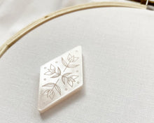 Load image into Gallery viewer, A diamond-shaped magnetic needle minder made of pearl acrylic, etched with a floral design.
