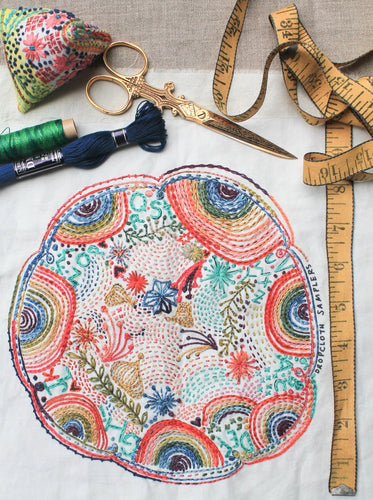 A colorful embroidery features rainbows, flowers and hidden letters.