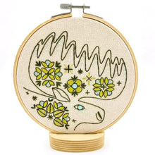 Load image into Gallery viewer, Embroidery hoop holds unbleached fabric stitched with a folk-style moose design, in greens and blues.
