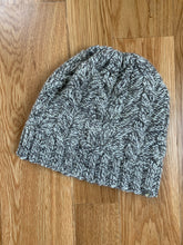 Load image into Gallery viewer, A white and gray marled cabled knit hat.
