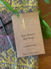 Load image into Gallery viewer, A brown paper box with gold letters holds a bar of The Great British Bee Company Raw Honey Bar Soap in Gardeners scent.
