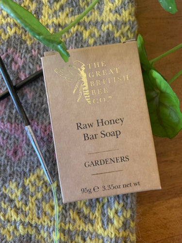 A brown paper box with gold letters holds a bar of The Great British Bee Company Raw Honey Bar Soap in Gardeners scent.