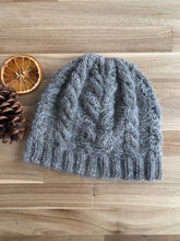 Load image into Gallery viewer, A gray wool hat knit in cables of alternating thickness and a ribbed brim.

