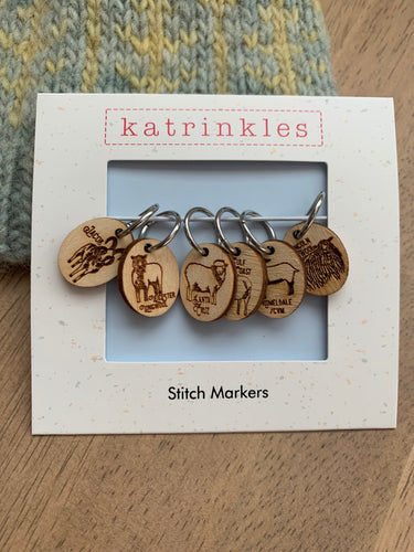 A set of 6 stitch markers made of wood, etched with pictures of 6 rare sheep breeds.