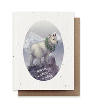 Load image into Gallery viewer, A greeting card of seed paper with an illustration of a mountain goat in a snowy setting, wearing a green wreath. The words &quot;warm winter wishes&quot; are written in cursive on the rock at his feet.
