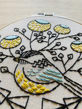 Load image into Gallery viewer, An embroidery hoop with a pattern of a chickadee and flowers in blue, yellow and black.
