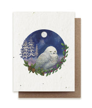 Load image into Gallery viewer, A greeting card on seed paper showing a circular illustration of a white snowy owl under moonlight, with snowy pines in the background and an evergreen branch in the foreground.
